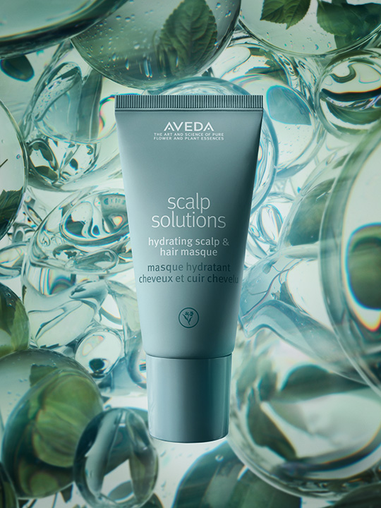 A tube of Aveda Scalp Solutions Hydrating Scalp & Hair Masque is displayed against a background of water, bubbles, and mint leaves.